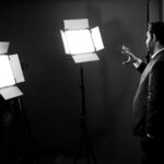 man in black jacket standing near white wall